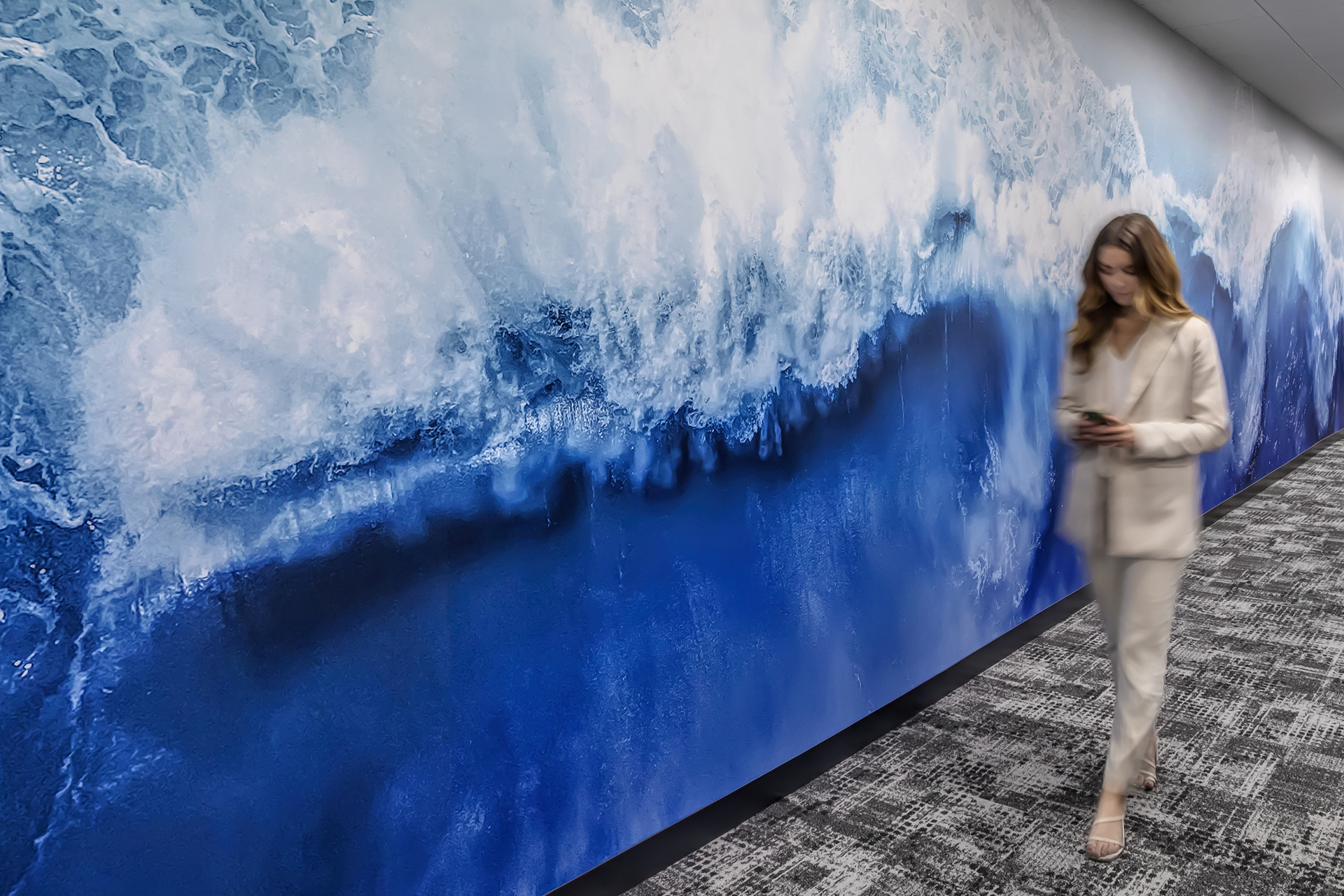 Woman walks by an ocean wall graphic